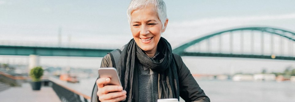 Woman on a bridge looking down at her phone.