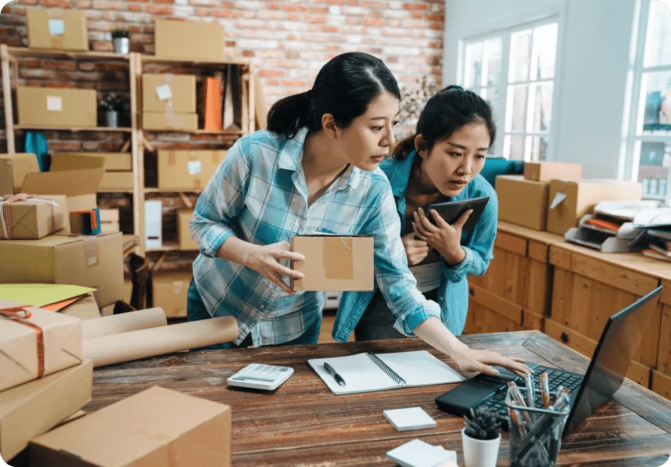 A business owner and employee prepare several packages for shipment.