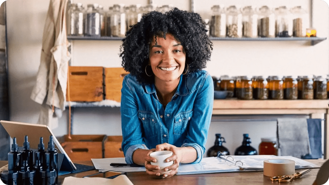 Smiling business owner standing behind the counter of her retail shop.