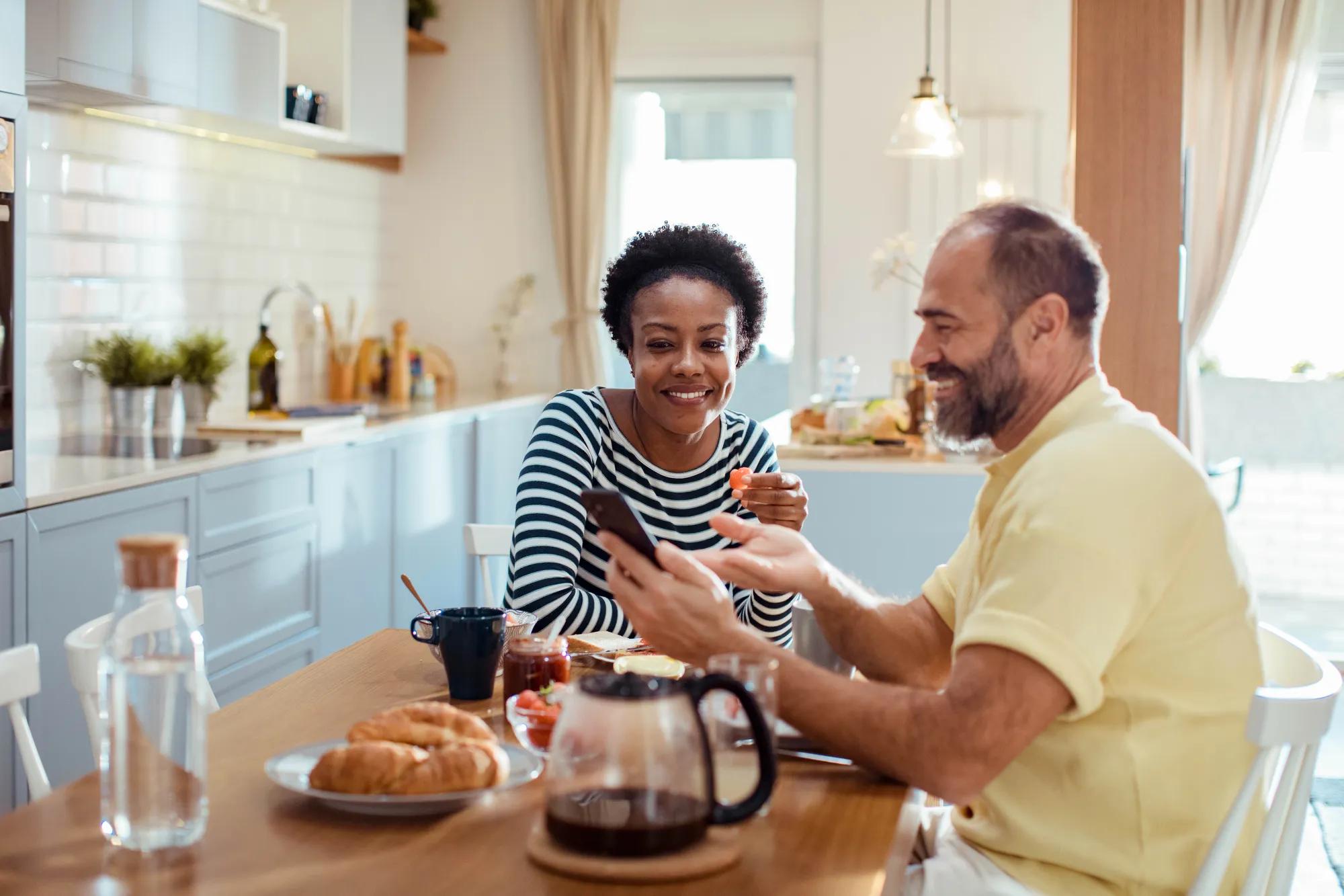 A man and a woman sitting at a table looking at a phone