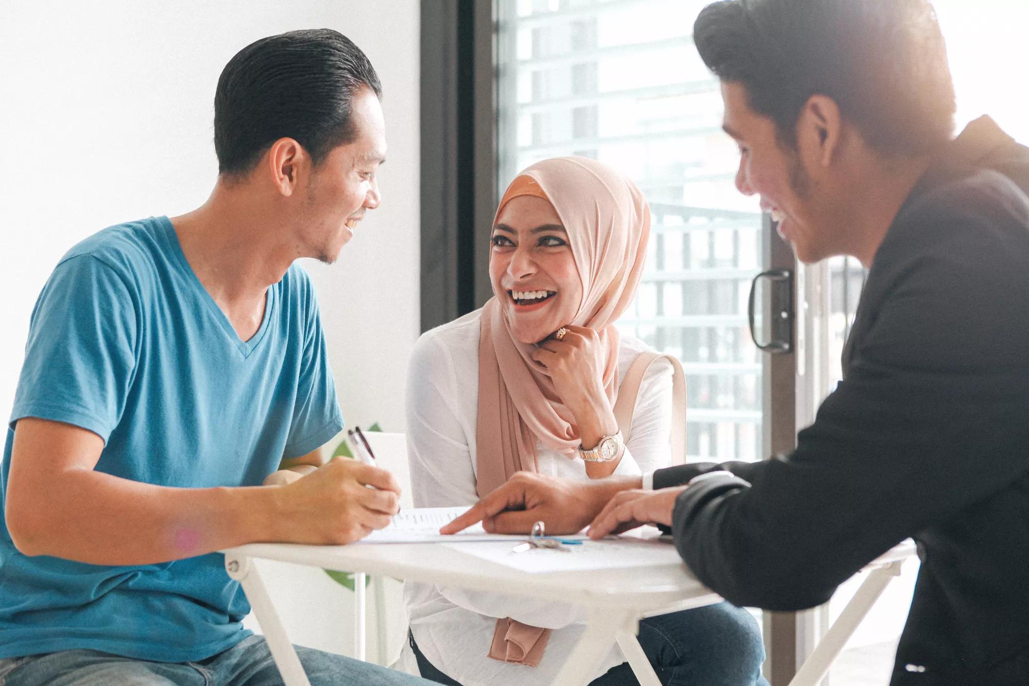 Three individuals collaborating at a table in an office environment.