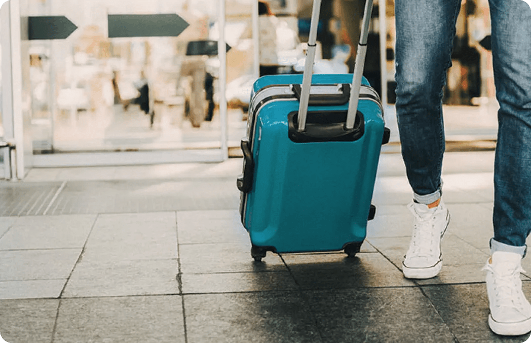 A person walking with a rolling suitcase.