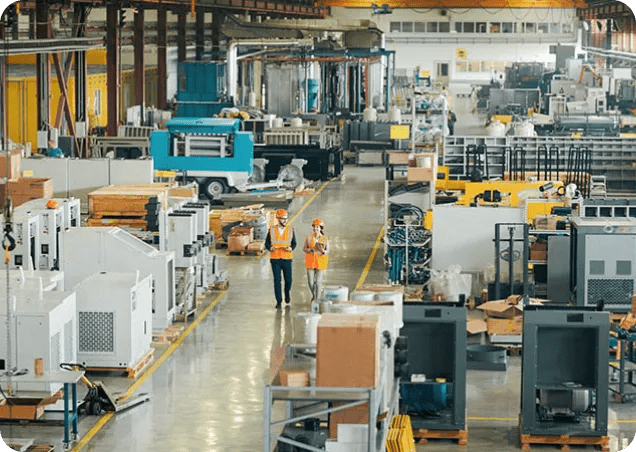 Two workers inspect a manufacturing warehouse.