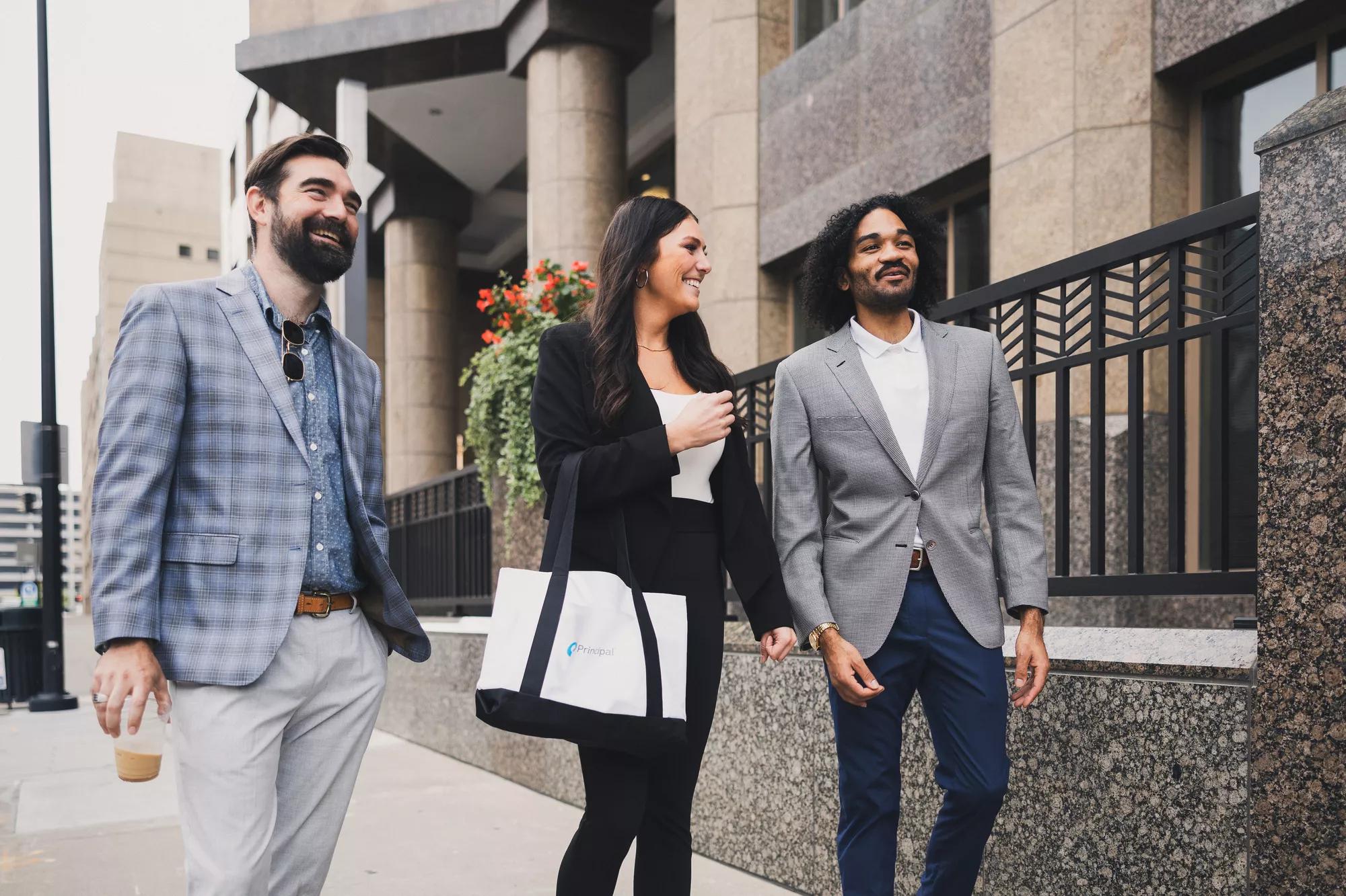 Three people walking outside of a 51ԹϺ building.